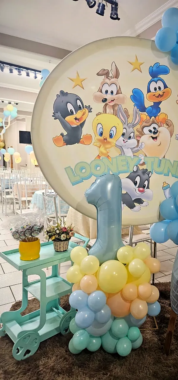 Painel Baby Looney Tunes com número 1 em balões e o salão ao fundo
